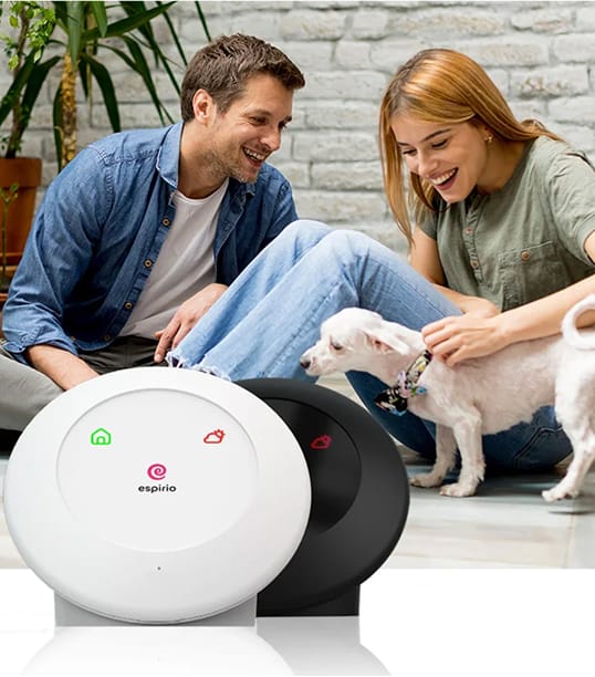 Uśmiechnięta para z białym psem, na pierwszym planie dwa urządzenia espirio w kolorze białym i czarnym